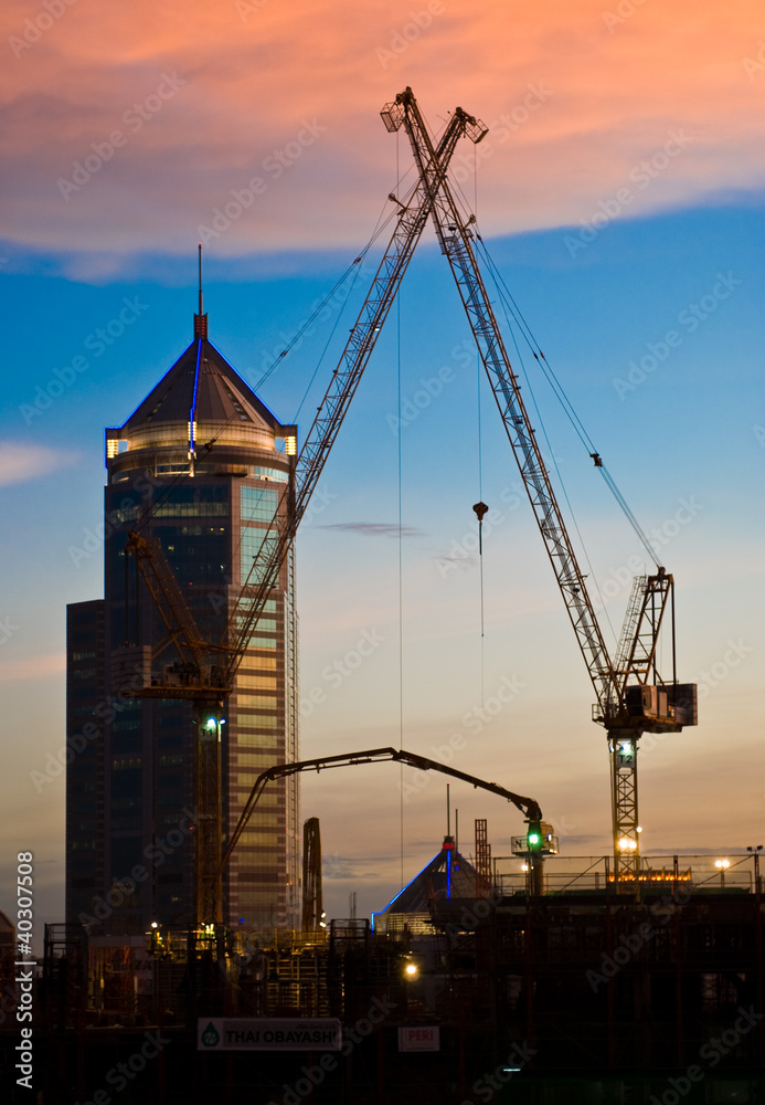 Derrick cranes at construction site at sunset time