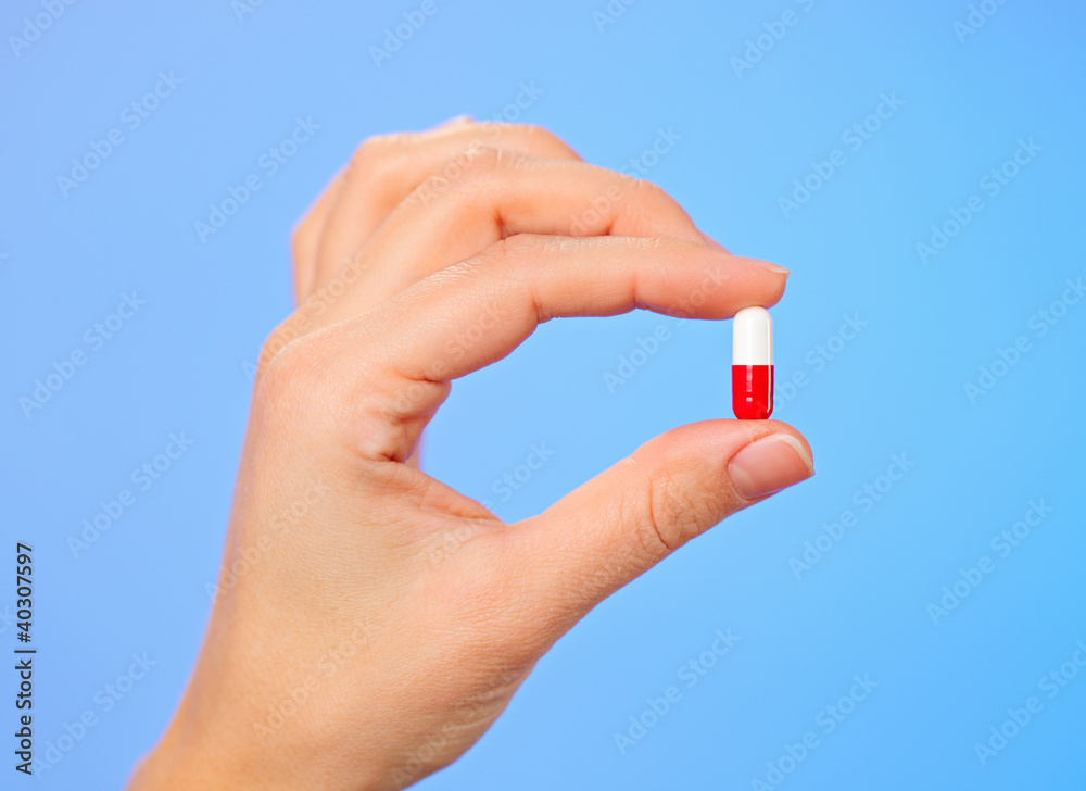 Red and white bolus (capsule) in doctor hand, macro view Red and white bolus (capsule) in doctor hand, macro view