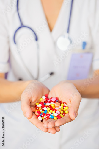 Pills, tablets and drugs heap in doctor's hand on blue backgroun