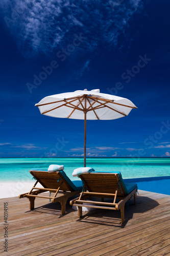 Deck chairs and infinity pool over tropical lagoon © Martin Valigursky