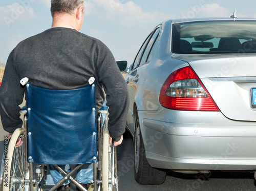 Man in a wheelchair next to his car photo