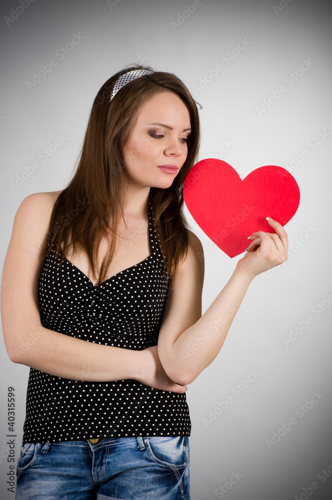 Beautiful young woman with red heart on dark background