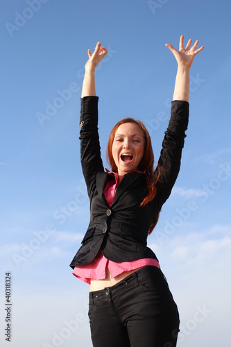 Pretty redhead woman is celebrating with hands up