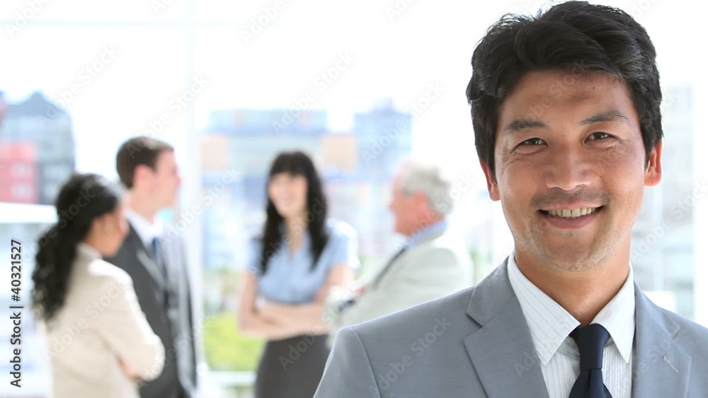 Happy businessman standing upright in front of his team Happy businessman standing upright in front of his team