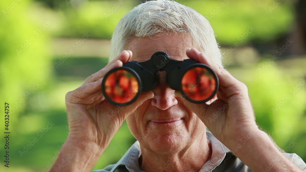 Smiling mature man looking through binoculars Smiling mature man looking through binoculars