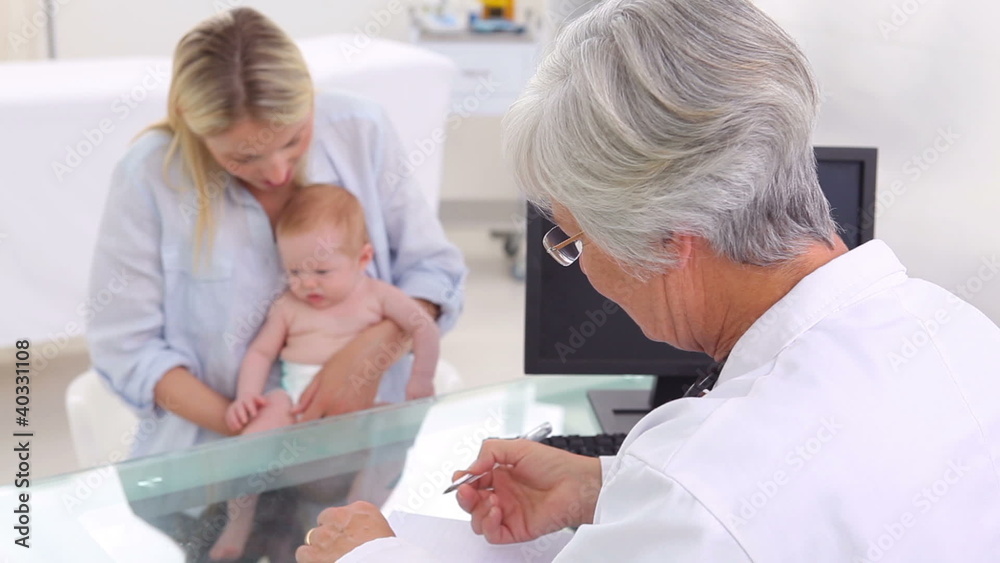 Little baby being held by her mother in front of the doctor Little baby being held by her mother in front of the doctor