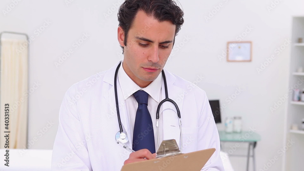Serious doctor holding his professional clipboard Serious doctor holding his professional clipboard