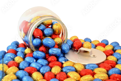 Glass jar with Easter eggs on a white background.