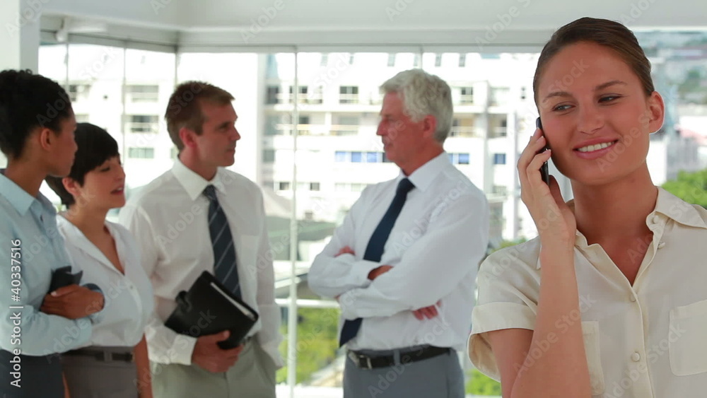 Business people talking with woman on the phone in foreground Business people talking with woman on the phone in foreground