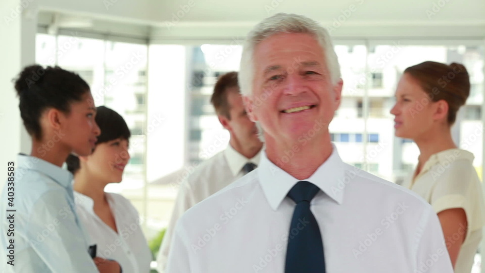 Smiling director posing with his employees in background Smiling director posing with his employees in background