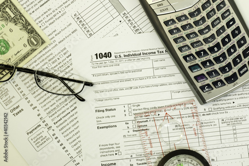 1040 tax form, calculator, glasses, compass and money