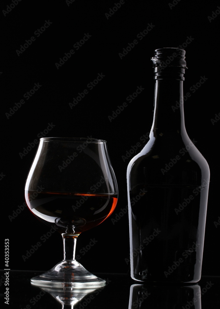 Glass of brandy and bottle on black background Glass of brandy and bottle on black background