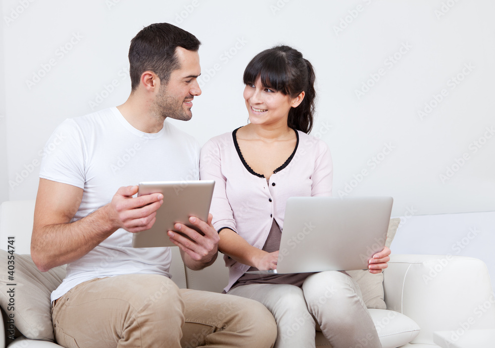 Young couple using laptops in couch Young couple using laptops in couch