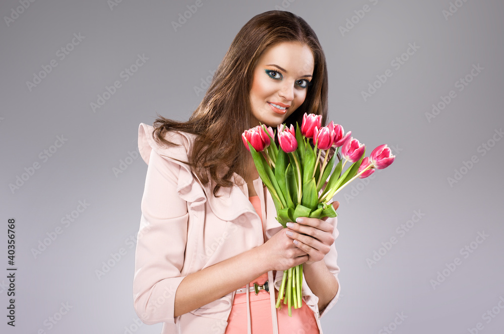 young brunette woman in pink coat holding flowers young brunette woman in pink coat holding flowers