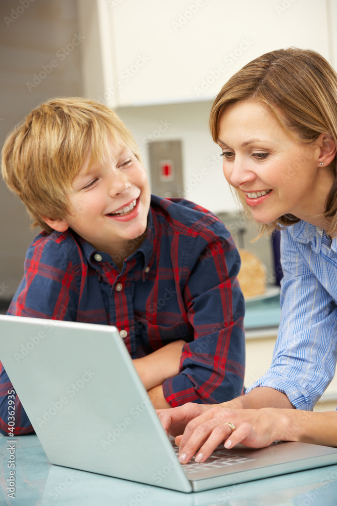 Mother and son using laptop in domestic kitchen Mother and son using laptop in domestic kitchen