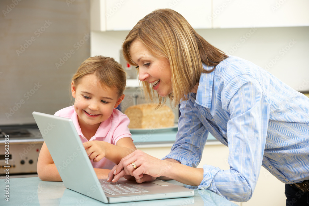 Mother and daughter using laptop in domestic kitchen Mother and daughter using laptop in domestic kitchen