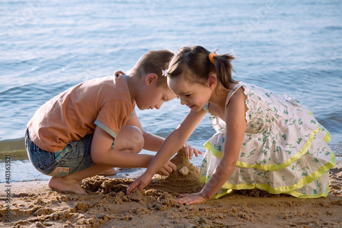 Cute little boy and girl playing in sand on beach