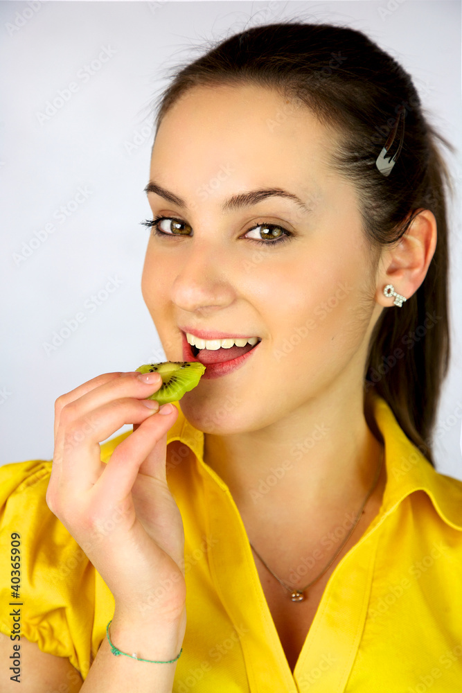 Beautiful girl eating fresh kiwi smiling happy Beautiful girl eating fresh kiwi smiling happy