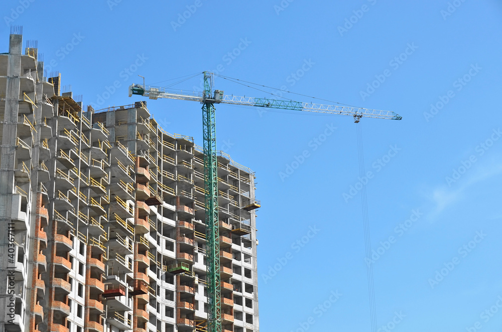 Building crane and building under construction against blue sky Building crane and building under construction against blue sky
