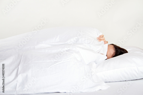 young woman in bed is hidding