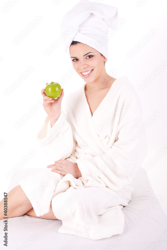 Beautiful young woman in a white spa bath robe eating a apple Beautiful young woman in a white spa bath robe eating a apple