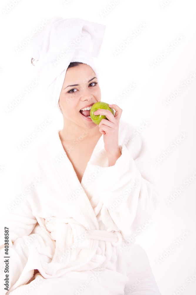 Beautiful young woman in a white spa bath robe eating a apple Beautiful young woman in a white spa bath robe eating a apple