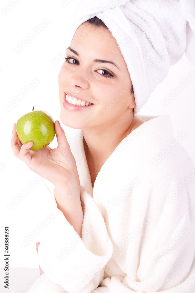 Beautiful young woman in a white spa bath robe eating a apple