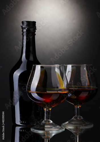 Glasses of brandy and bottle on gray background