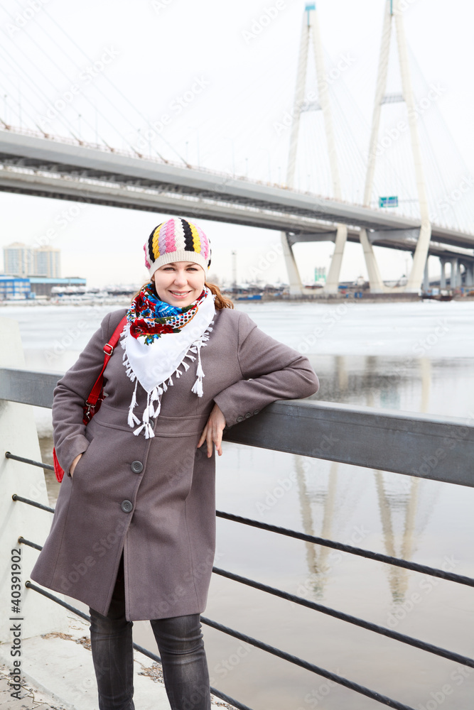 Obraz premium Happy young female with scarf standing on embankment