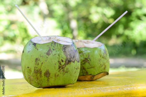 Tropical green coconuts opened for the water with straws