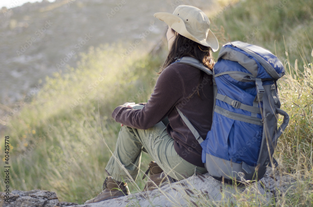 Young woman taking a break and admiring the view on hiking trip