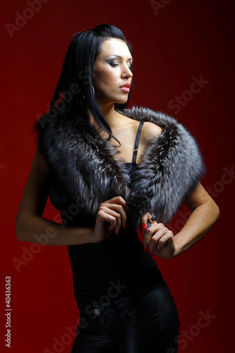 Image of glamorous woman wearing a fur. Red background