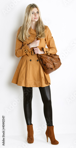 standing woman wearing coat and fashionable brown shoes with a h