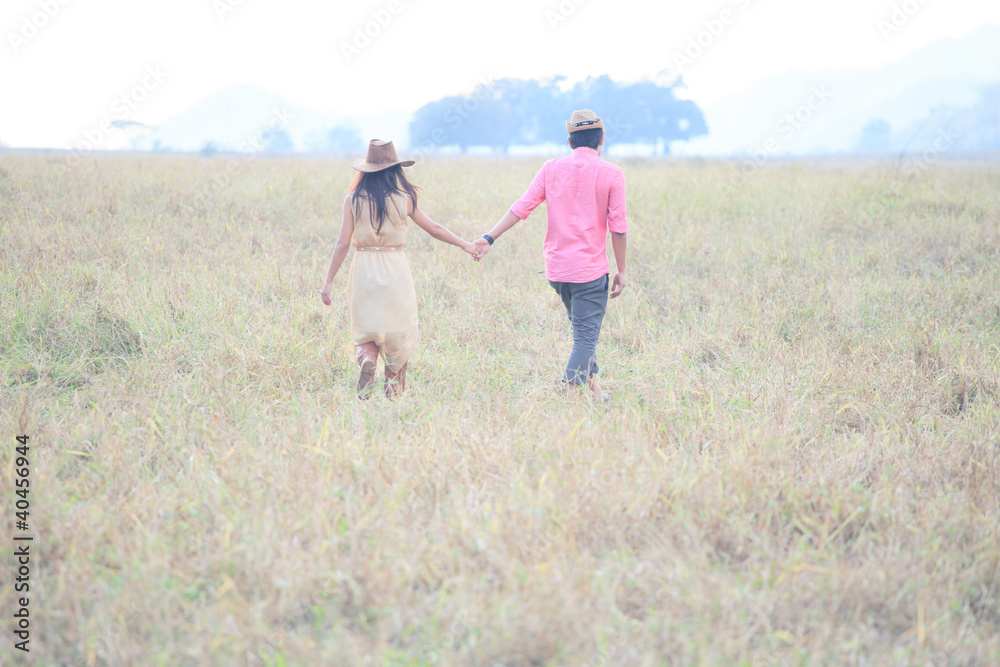 man and women wearing a hat walking in the grass field