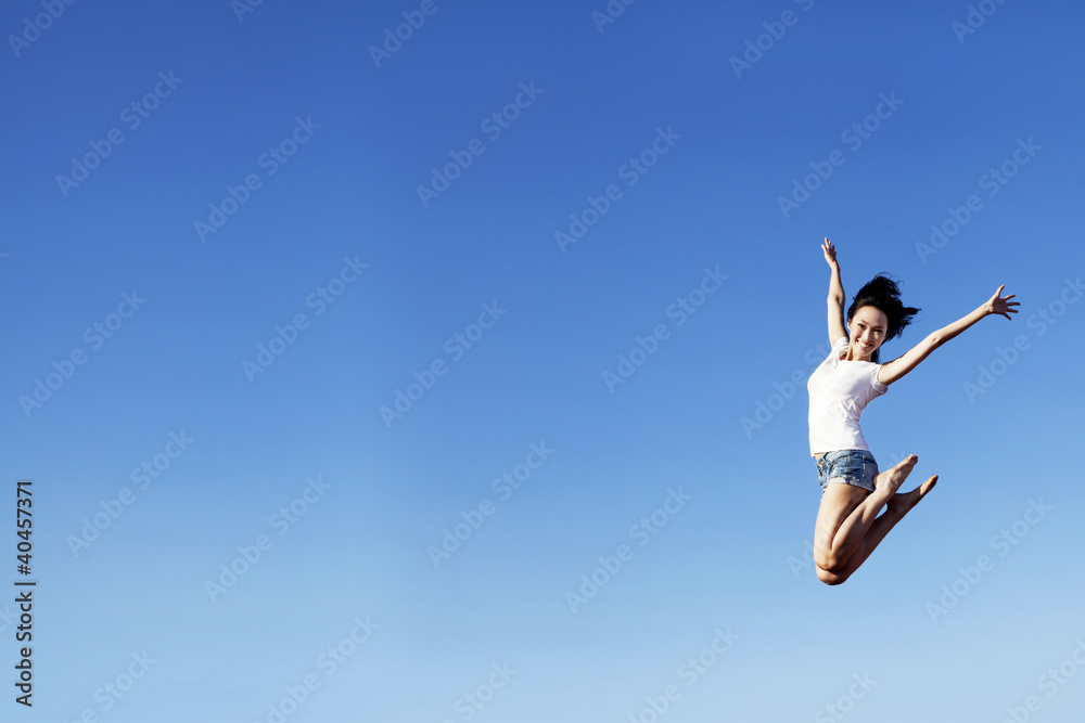 Joyful woman jumping over clear blue sky