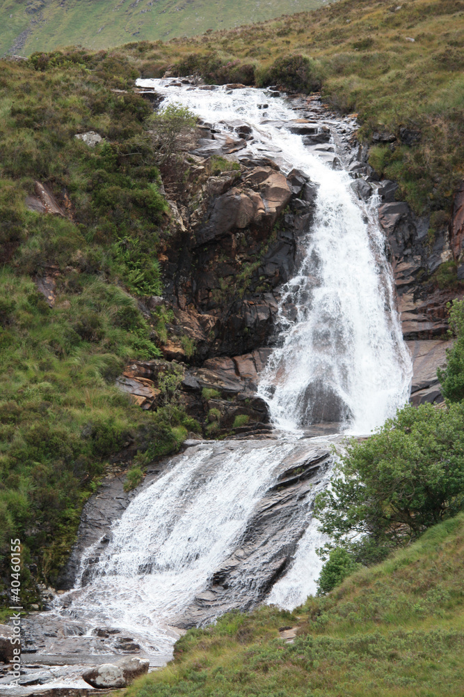 Obraz premium A Mountain Stream Flowing Over a Waterfall.