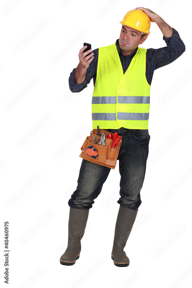 confused builder looking at mobile telephone confused builder looking at mobile telephone