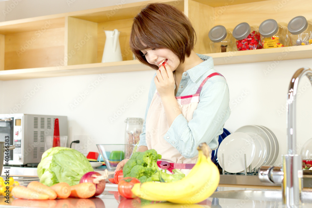 Beautiful young woman in kitchen making salad. Portrait of asian