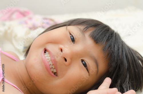 Smiling Asian girl lay down on bed