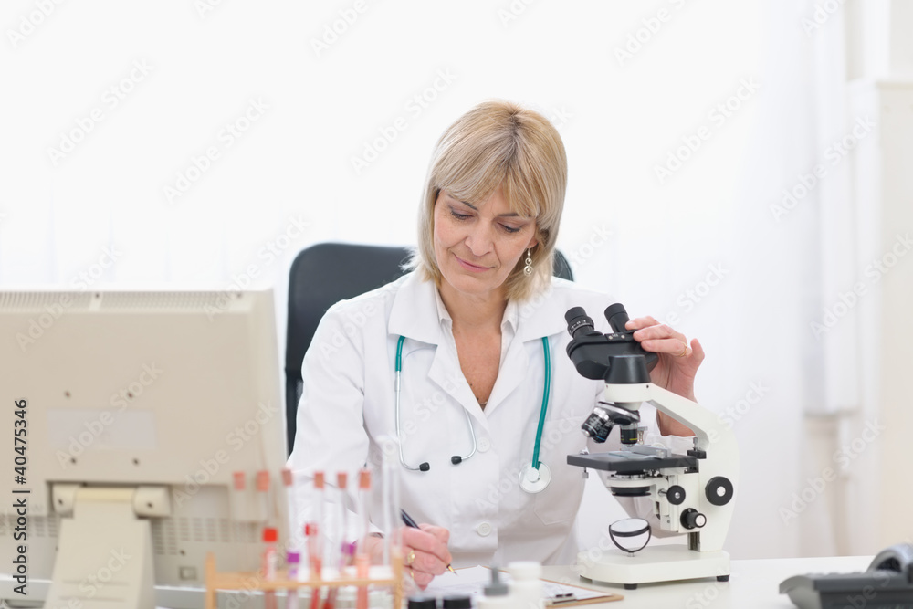 Middle age doctor woman working with microscope Middle age doctor woman working with microscope