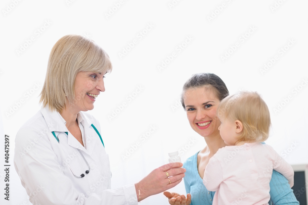 Pediatric doctor giving pills bottle to mother with baby Pediatric doctor giving pills bottle to mother with baby