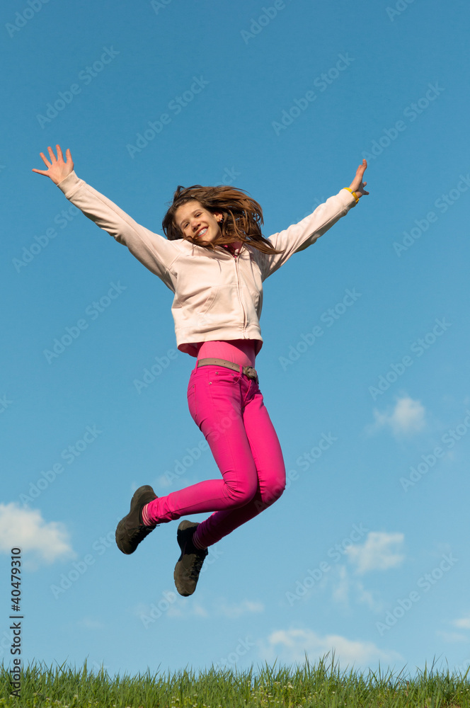 Cute teenage girl jumping with joy on sunny spring day