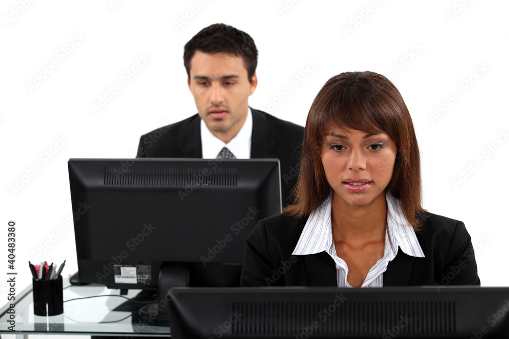 Two office workers sat at their desks Two office workers sat at their desks