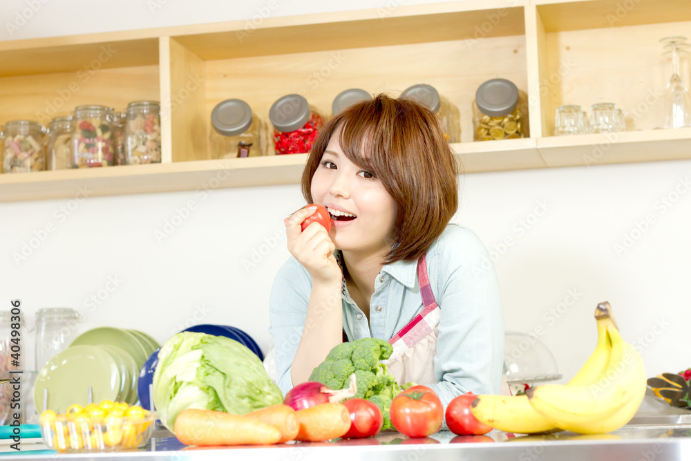 Beautiful young woman in kitchen making salad. Portrait of asian