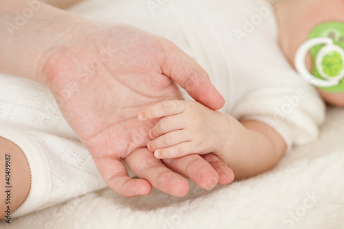 parent's hand holding baby's hand