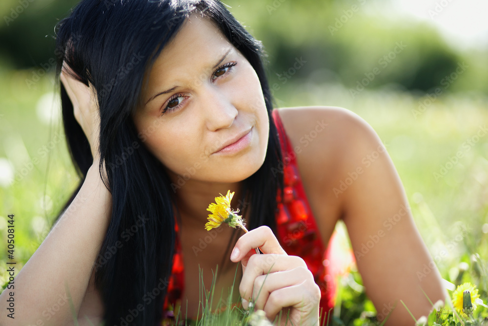 Beautiful woman lying in the garden holding a dandelion Beautiful woman lying in the garden holding a dandelion
