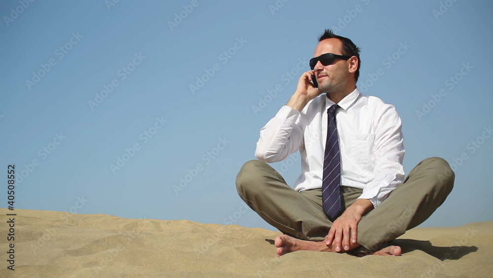 Young businessman talking on cellphone in the desert Young businessman talking on cellphone in the desert