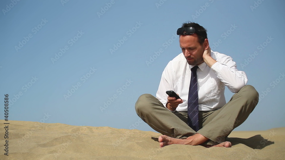 Young businessman using smartphone in the desert Young businessman using smartphone in the desert