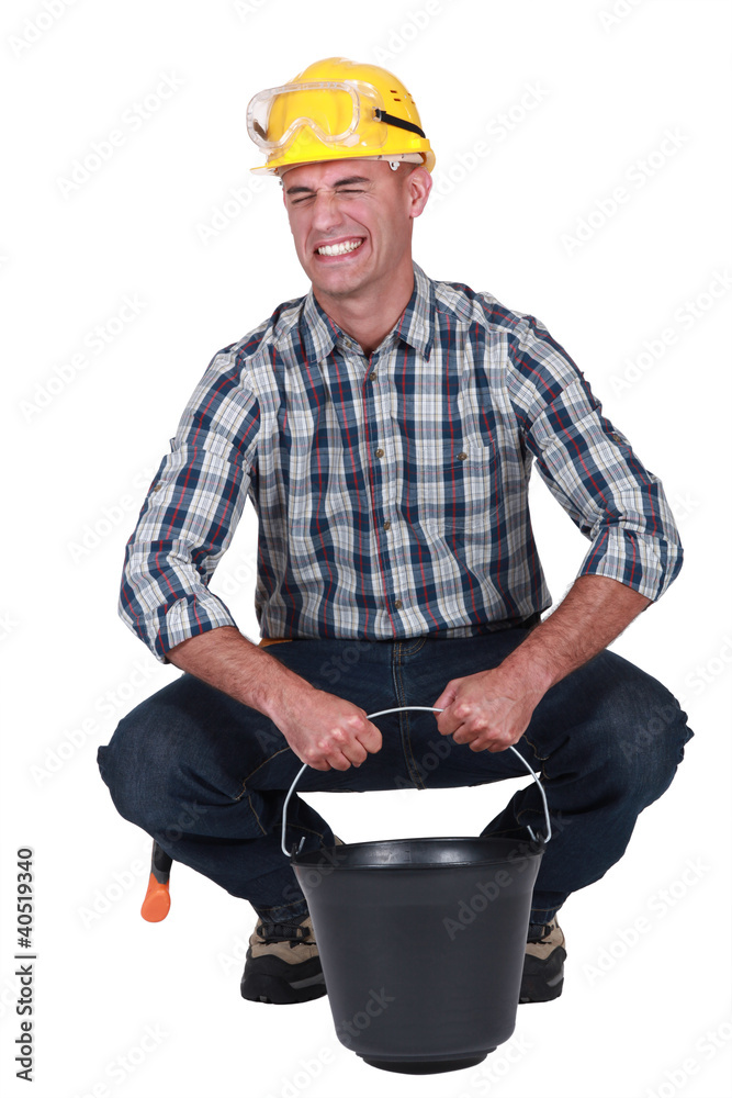 Labourer struggling to lift a heavy bucket