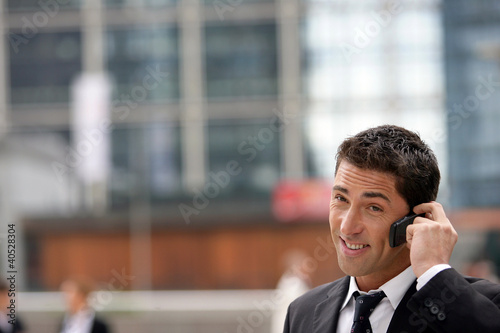 Yuppie businessman making a call outside office photo